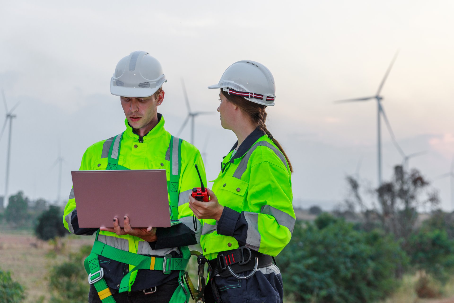 An engineer in safety uniform on a civil site holding a tablet, completing a digital site inspection that replaces the paper clipboard